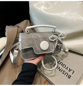 Detail of grey denim texture handbag with white button and pearl bow charm accessory