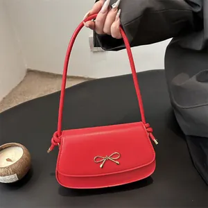 Chic red shoulder bag with golden bow clasp and stylish knotted rope strap detail