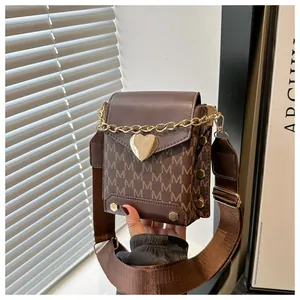 Détail du mini sac bandoulière marron vintage avec boucle cœur dorée et imprimés
