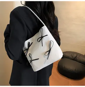 Detail showing white bucket tote bag with decorative black bow knots on smooth faux leather
