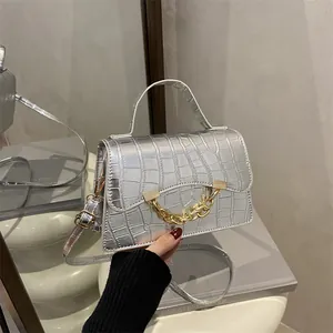 Silver crocodile pattern box bag with bold gold chain and top handle on a white stand