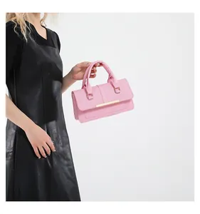 Sac à main rose rectangulaire avec barre dorée porté par un mannequin en robe noire