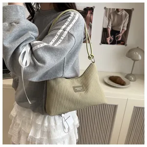 Détail du sac seau vert avocat plissé avec texture verticale et écusson en cuir