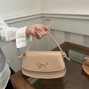 Elegant beige underarm handbag with gold bow detail and curved handle for women
