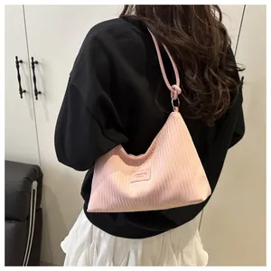 Détail du sac seau en velours côtelé rose avec anneaux métalliques et étiquette cuir