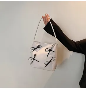Detail of white bucket tote bag with black decorative bows and soft leather texture
