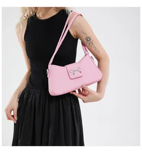 Detalle del bolso baguette rosa con lazo plateado y un acabado con textura elegante