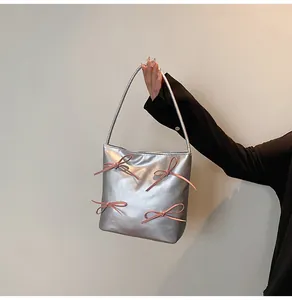 Detail of silver metallic tote bag with pink bows and smooth mirror finish leather