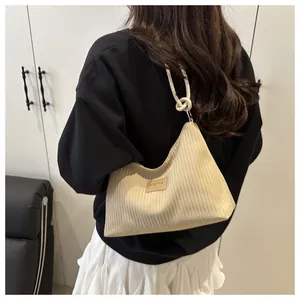 Détail du sac seau en velours beige avec poignée nouée et étiquette en cuir JINGPIN