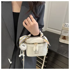 Detail of white fashion bucket bag with silk scarf handle and plush monster charm