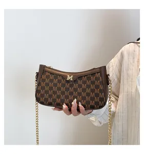 Close-up of brown letter pattern shoulder bag featuring golden M logo and metal chain strap