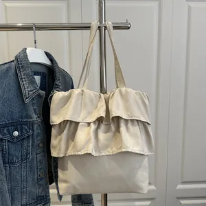 Beige pleated tote bag with layered ruffle design and soft matte texture for women