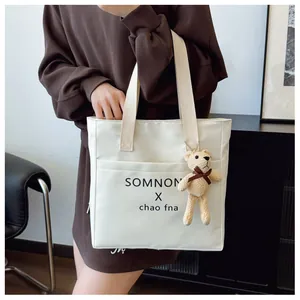 White minimalist tote bag featuring black letter print and cute beige bear charm detail