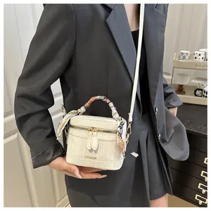 Detail of white mini bucket bag with fashion print and silk scarf handle decoration