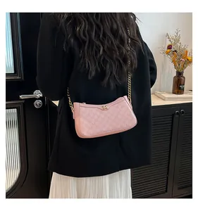 Detail of pink shoulder bag with M-letter embossing and golden chain strap on model