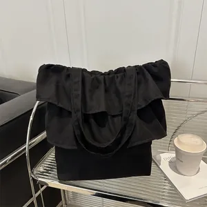Minimalist black ruffled canvas tote bag featuring a tiered design on a stylish display shelf