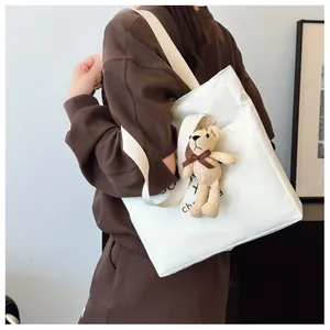 Detailed shot of white tote bag with letter print and brown plush bear charm