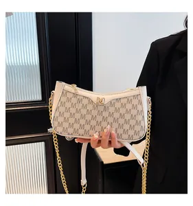Detail of monogram M print on cream crossbody bag with gold logo and chain strap