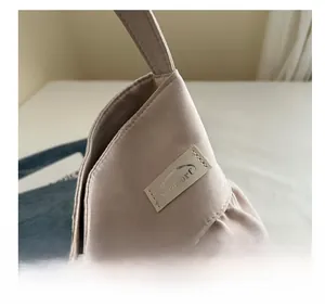 Dettaglio della borsa tote in tessuto beige con volant, cuciture ed etichetta Noroorf