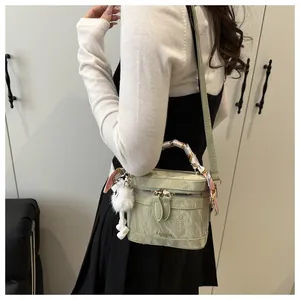 Close-up of marble texture shoulder bag with silk scarf handle and white pom-pom charm