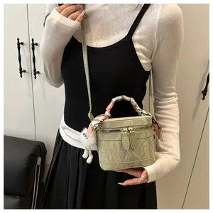 Detail of light green bucket bag with wrinkled texture and scarf-wrapped handle