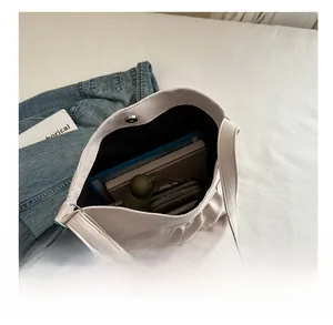Dettaglio della grande borsa tote beige in tela con design a pieghe e chiusura magnetica