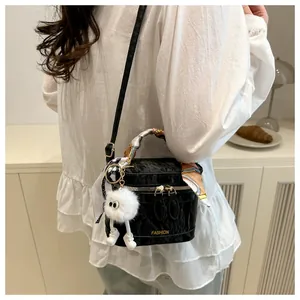 Close-up of black crossbody bag with silk scarf handle and white plush monster charm