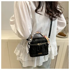Close-up of black pleated mini bucket bag with fashion print silk scarf on handle