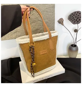 Detail der Wildleder-Beuteltasche mit weißem Kunstpelzbesatz und goldenem Glocken-Anhänger