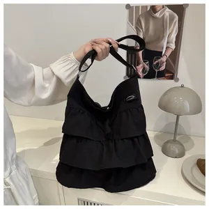 Dettaglio della borsa tote in tela nera con bordo a tre strati di volant e logo cucito