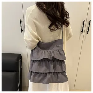 Dettaglio del design a balze multistrato di questa borsa tote in tessuto grigio su modella