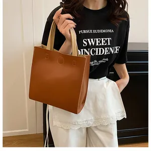 Détail du sac cabas marron montrant les coutures fines et la poignée crème contrastée