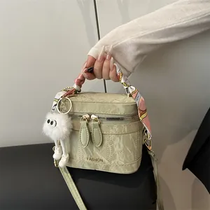 Light green leather crossbody bucket bag with silk scarf handle and plush charm