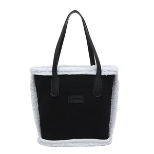 Schicke schwarze Handtasche mit weißem Kunstpelzbesatz und modischem Label-Design