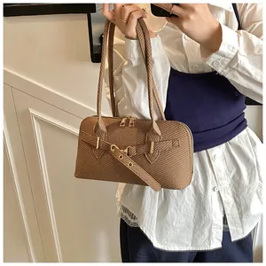 Detailed close-up of brown textured woven leather shoulder bag with buckle and dual zippers