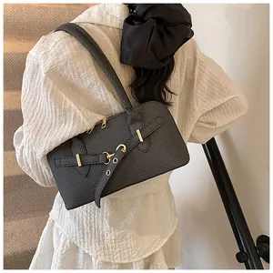 Detail of black textured pillow bag featuring golden zippers and stylish buckle accents