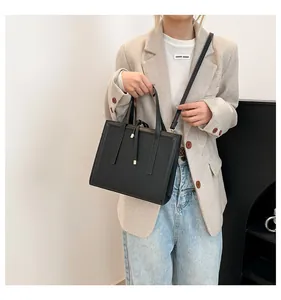 Detail of black leather square crossbody bag with metallic accents and thin straps