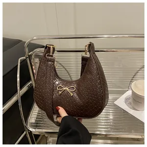 Detail of dark brown hobo bag with woven texture and gold bow metal accessory