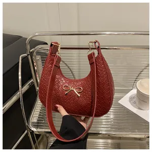 Close-up of wine red woven leather shoulder bag with a gold bow metal accent