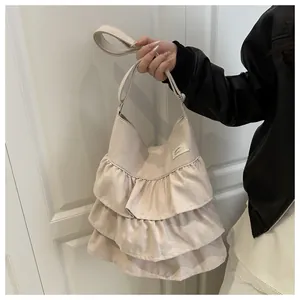 Dettaglio del design a balze multistrato e trama del tessuto di una borsa beige