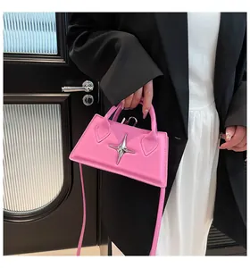Détail d'un sac rose avec emblème d'étoile argentée porté sur un blazer noir