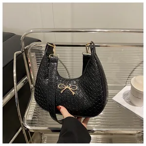 Detailed close-up of woven texture and golden bow buckle on black hobo shoulder bag