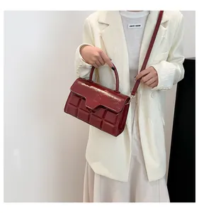 Detail van bordeauxrode crossbodytas met chocoladegitstructuur en glanzend lederen afwerking