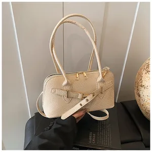 Close-up of woven beige shoulder bag featuring golden zippers and decorative buckle strap