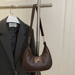 Dark brown crescent moon shoulder bag with crocodile pattern and golden bow accent