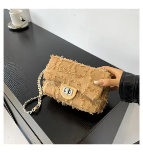 Détail du sac à chaîne en tissu kaki avec fermoir rotatif argenté sur bois sombre