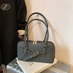 Dark gray textured pillow bag with gold zippers and decorative straps on a suitcase