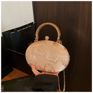 Dettaglio della borsa da sera in raso beige con ricamo floreale e manico dorato