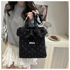 Détail du sac cabas noir à volants avec motifs floraux blancs et étiquette en tissu
