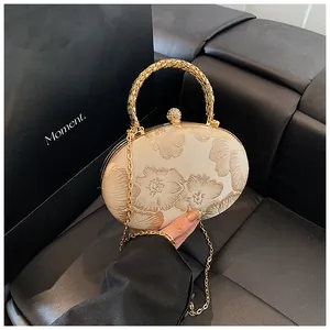 Dettaglio dell'elegante borsa da sera con ricamo floreale, manico oro e chiusura cristallo